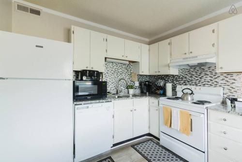 una cocina con armarios blancos y electrodomésticos blancos en Cute Condo in Rock Hill-45, en Rock Hill