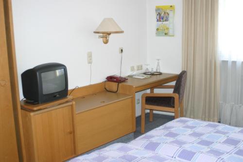 a bedroom with a desk with a tv on a dresser at Gasthof Napoleon in Selbitz