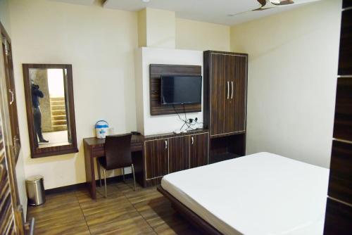 a bedroom with a bed and a desk with a television at Hotel Midtown & Restaurant in Jhunjhunūn