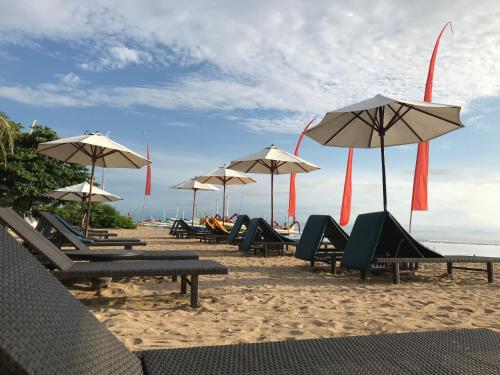 Un grupo de sillas y sombrillas en una playa. en Besakih Beach Hotel, en Sanur