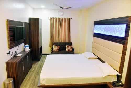 a bedroom with a bed and a tv and a chair at Hotel Midtown & Restaurant in Jhunjhunūn