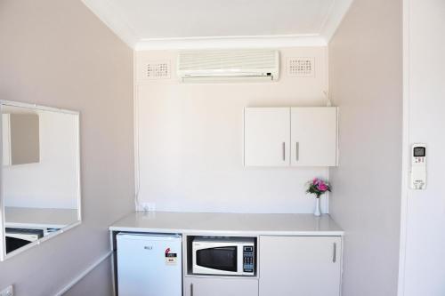 a kitchen with white cabinets and white appliances at Hillview Motel in Goulburn
