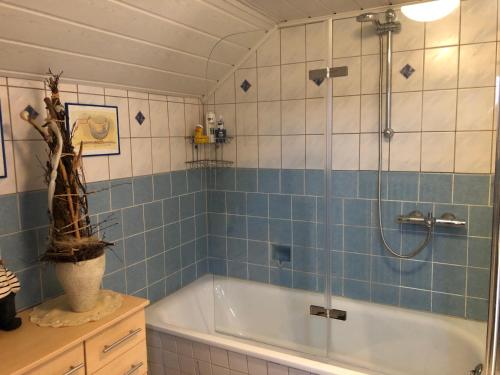 a bathroom with a tub and a shower with blue tiles at Ferienhaus Nordseerobbe in Friedrichskoog