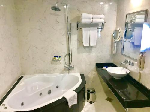 a bathroom with a large tub and a sink at Samaya Hotel Deira in Dubai