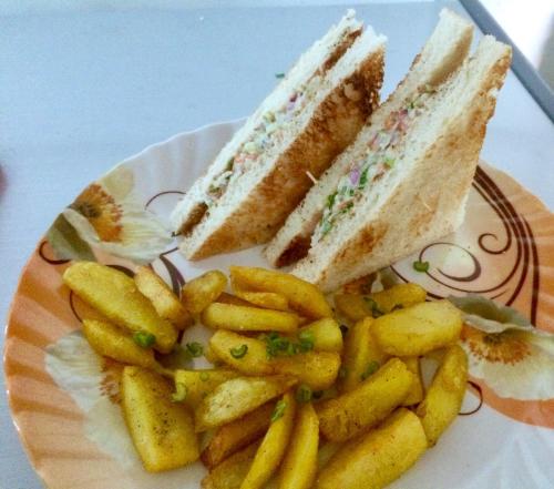 a plate with a sandwich and french fries on it at Gorkha Chhen bed & breakfast in Gorkhā