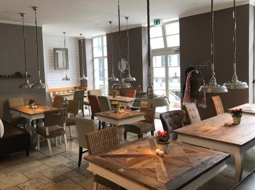 ein Restaurant mit Holztischen, Stühlen und Fenstern in der Unterkunft Suite Hotel Binz Familienhotel Rügen klimaneutral in Binz