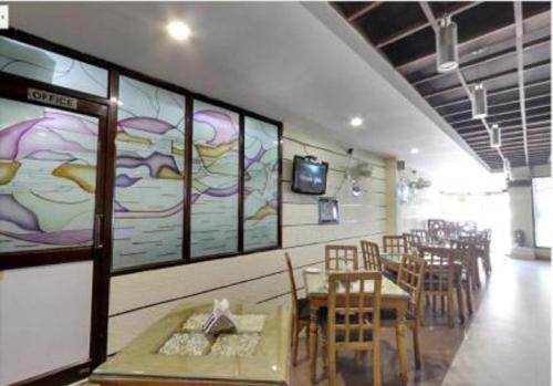 a restaurant with tables and chairs and a tv on a wall at Hotel Landmark in Haridwār