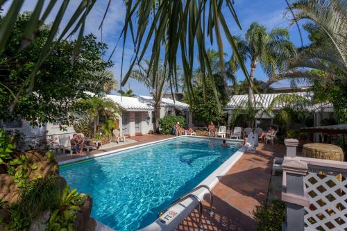 a swimming pool with palm trees and people sitting around it at Richard's Motel in Hollywood