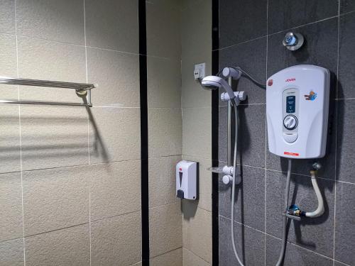 a shower in a bathroom with a phone on the wall at Hotel Centre Point Tampin in Malacca