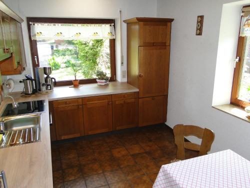 une cuisine avec des placards en bois, une fenêtre et une table dans l'établissement Ferienhaus Luhetalblick Prescher, à Bispingen