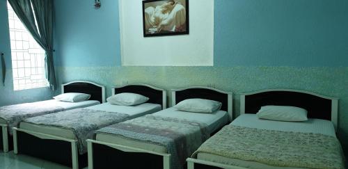 three beds in a room with blue walls at Bac Huong Hotel in Kon Tum