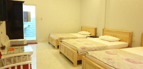 a room with three beds and a tv in it at Bac Huong Hotel in Kon Tum