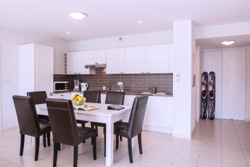 a kitchen with a white table and chairs in a room at L'Ecrin du Lac in Chorges