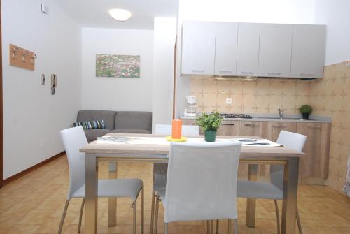 cocina con mesa de madera y sillas blancas en Appartamenti Dei Fiori, en Lignano Sabbiadoro