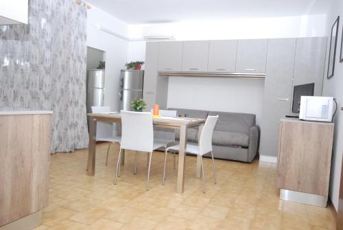 cocina y comedor con mesa y sillas blancas en Appartamenti Dei Fiori, en Lignano Sabbiadoro