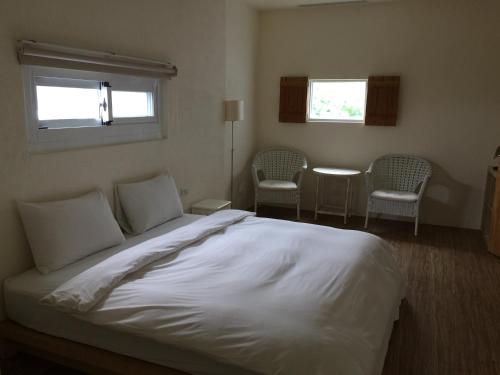 a bedroom with a large white bed and two chairs at Seashore My Home in Eluan