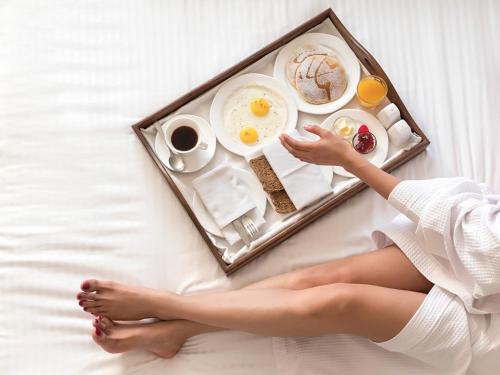 a woman laying on a bed with a tray of breakfast at Ratan Vilas, Jodhpur in Jodhpur