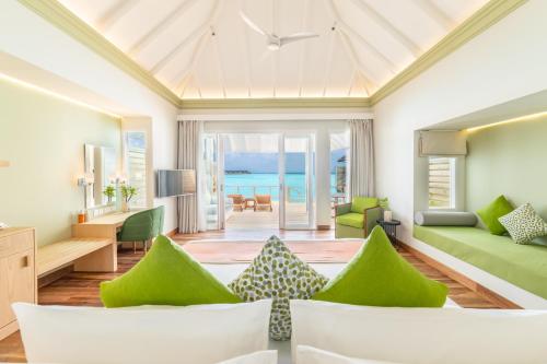 - un salon doté d'un mobilier vert et offrant une vue sur l'océan dans l'établissement Sun Siyam Olhuveli, à Atoll Malé Sud