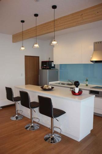 a kitchen with a large white island with chairs at Diamond Dust Furano in Furano