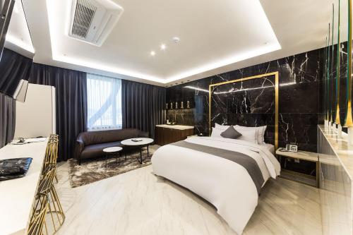 Astro Hotel في يونغين: غرفة نوم بسرير ابيض كبير وجدار اسود