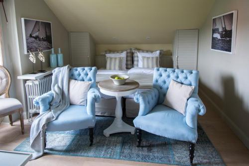 - une chambre avec 2 chaises bleues, une table et un lit dans l'établissement Lebeau 19 Hotel, à Knokke-Heist
