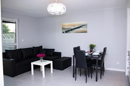 sala de estar con sofá negro y mesa en Apartament z ogródkiem, en Trzęsacz