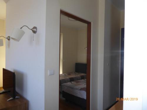 a door to a bedroom with a bed and a mirror at Kantal Apartamenty Hel in Hel