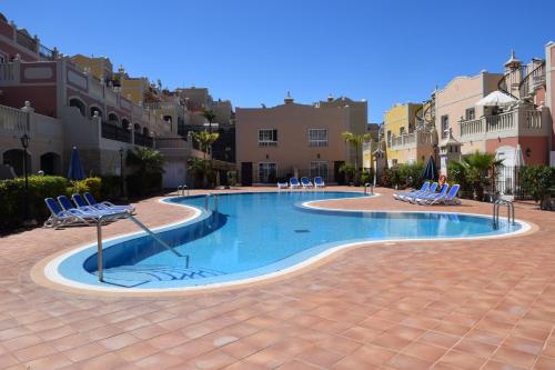 una piscina en un patio con sillas y edificios en Orion, en Palm-mar