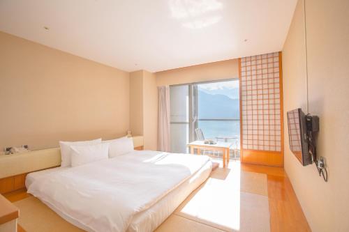 Un dormitorio con una gran cama blanca y una ventana en Hotel Del Lago, en Yuchi