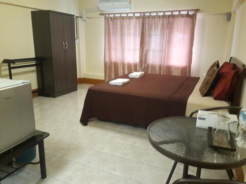 a room with a bed and a table and a window at Relax Inn in Ban Phe