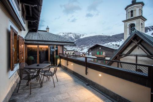 a balcony with a table and chairs and a church at Hotel Compagnoni in Livigno
