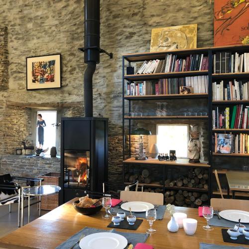een eetkamer met een tafel en een open haard bij Les Rochers in Cerisy-la-Forêt