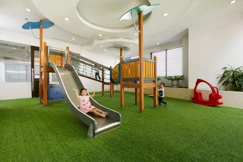 a little girl sitting on a slide in a play room at Grande Centre Point Hotel Ratchadamri Bangkok in Bangkok