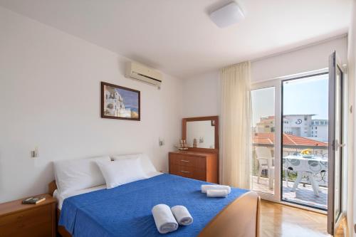 a bedroom with a blue bed with two towels on it at Apartment Ivanovic Family in Becici