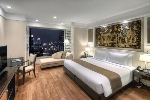 バンコクにあるグランデ センター ポイント ホテル ラチャダムリ バンコクのベッドルーム(大型ベッド1台付)、リビングルームが備わります。