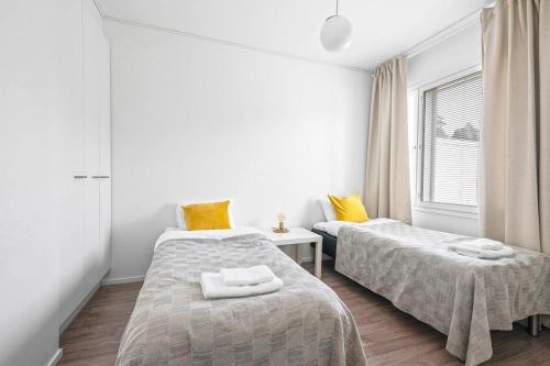 two beds in a white room with yellow pillows at Hämeentie Apartments in Järvenpää