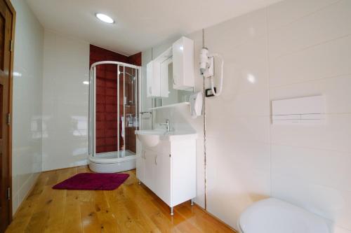 La salle de bains blanche est pourvue d'un lavabo et d'une douche. dans l'établissement Villa Panorama, à Međugorje