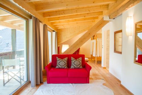 a red couch in a room with a large window at Beauty & Vital Hotel Maria in Carano