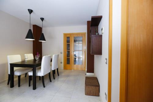 a dining room with a black table and white chairs at Maldivas Planet Costa Dorada in La Pineda