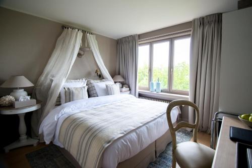 a bedroom with a canopy bed and a window at Lebeaubylivingroom Hotel in Knokke-Heist