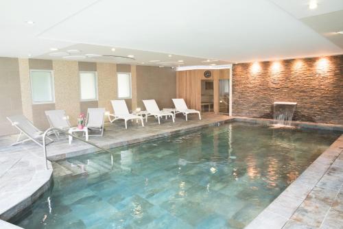 - une piscine avec des chaises blanches et une table dans l'établissement Château Belmont Tours by The Crest Collection, à Tours