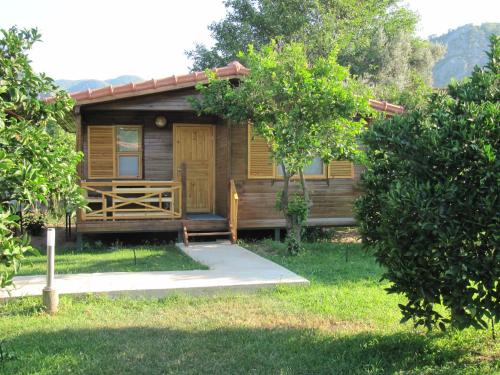 a wooden cabin with a porch and a door at Baris Pension & Bungalows in Cıralı