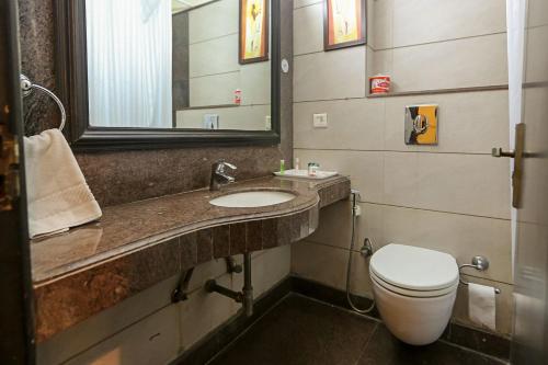 a bathroom with a toilet and a sink and a mirror at The Oakland Plaza by Orion Hotels in New Delhi