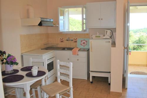cocina con mesa pequeña y nevera blanca en Lefkothea Apartments en Kassiopi
