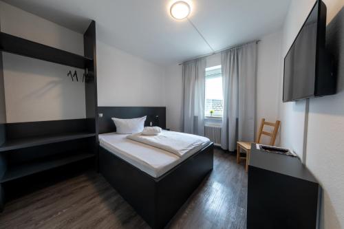 um pequeno quarto com uma cama e uma televisão em Hotel Central em Menden