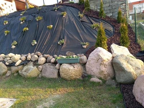 a garden with rocks and a black tarp and plants at Pokoje gościnne Venezia in Czaplinek