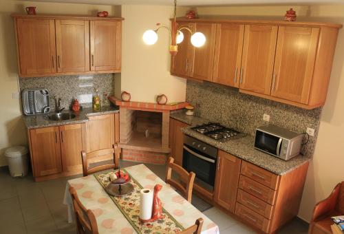 a kitchen with wooden cabinets and a table and a microwave at Vivenda Agostinho (Casa de Férias) in Arcos de Valdevez