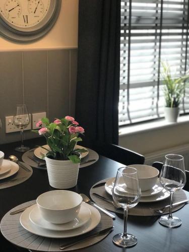 a table with plates and wine glasses and a clock at Glaisdale Apartment in Wolverhampton