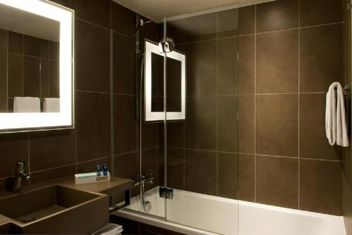 a bathroom with a sink and a tub and a mirror at Novotel Marseille Centre Prado Vélodrome in Marseille