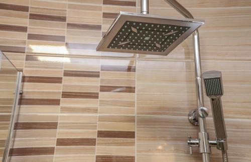 a shower head in a bathroom with a tile floor at Hotel ZRINSKI in Koprivnica